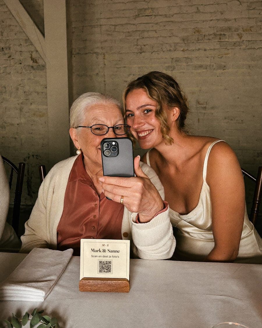 Oma maakt een selfie met haar kleindochter, met het QR-kaartje op tafel