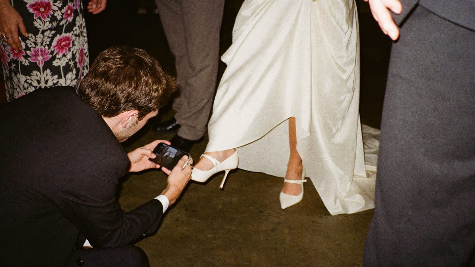 Een gast hurkt om de trouwschoenen van de bruid te fotograferen