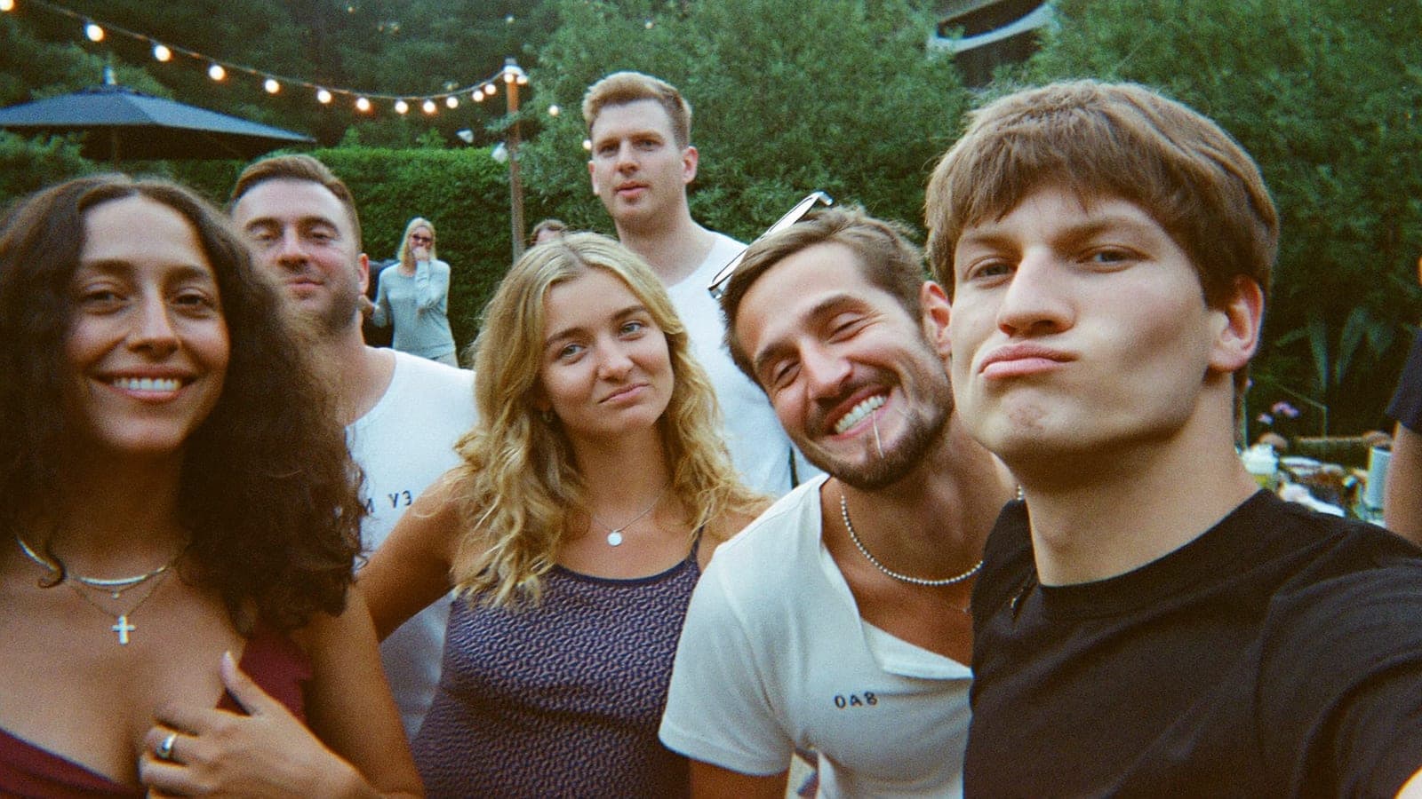 Gekke groepsselfie op een tuinfeest onder de lichtslingers