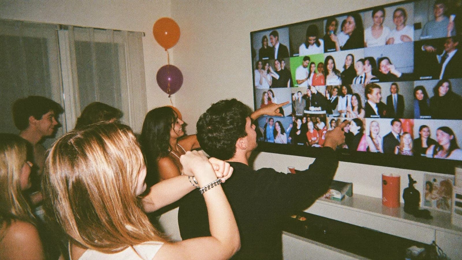 Feestgasten wijzen lachend naar de live fotomuur op de tv