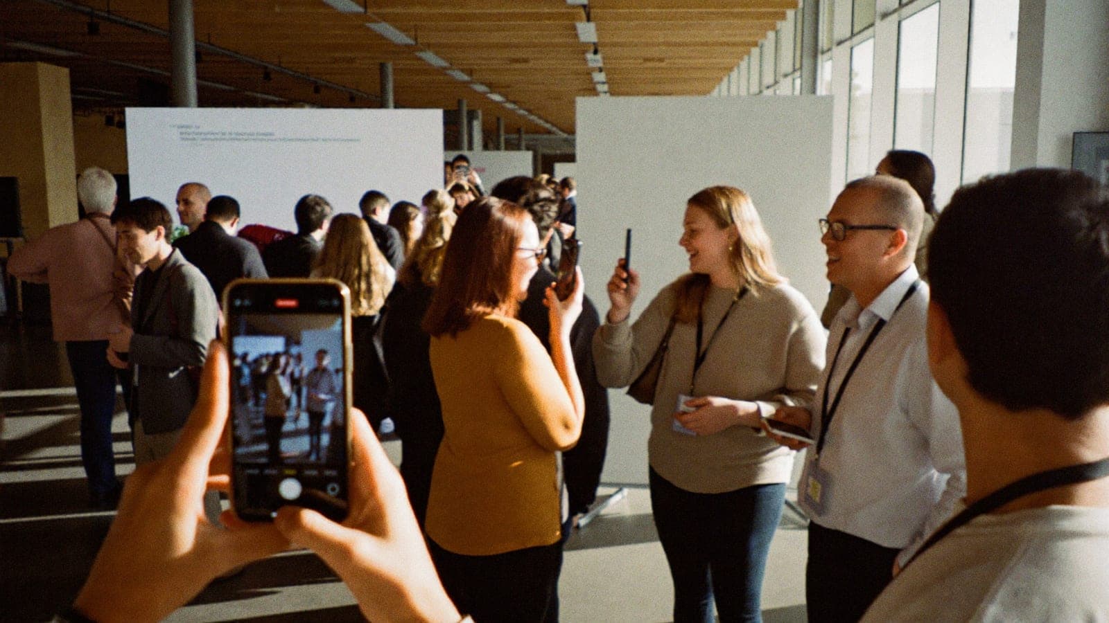 Bezoekers van een congres maken foto's met hun telefoon in de foyer tijdens de koffiepauze