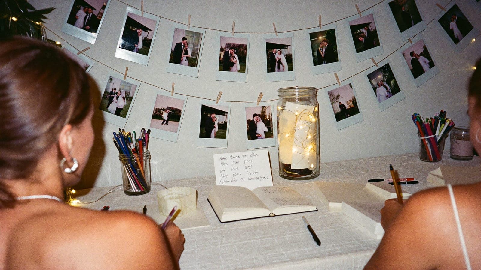Gastenboektafel met een lijn vol polaroids, pennen en een pot met lichtjes