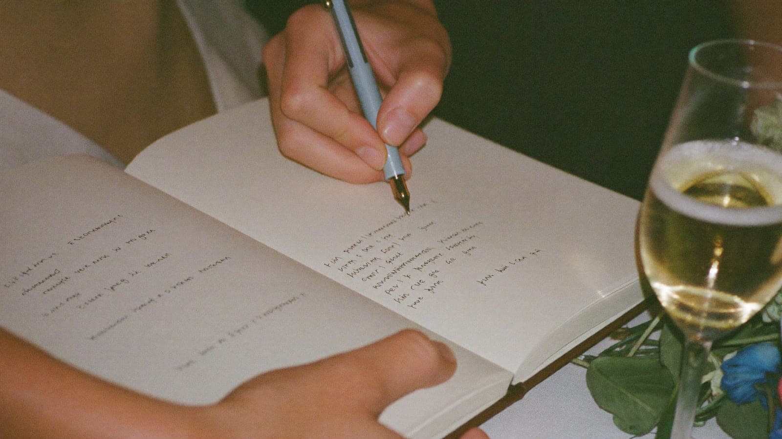 Een hand schrijft met een vulpen een tekst in het gastenboek