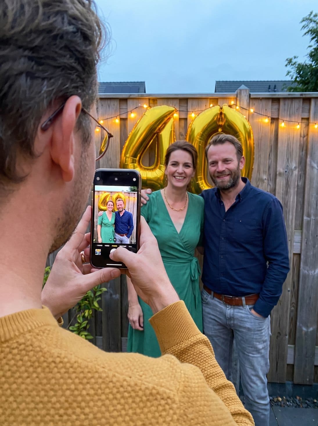 Een gast fotografeert de jarige voor de 40-ballonnen