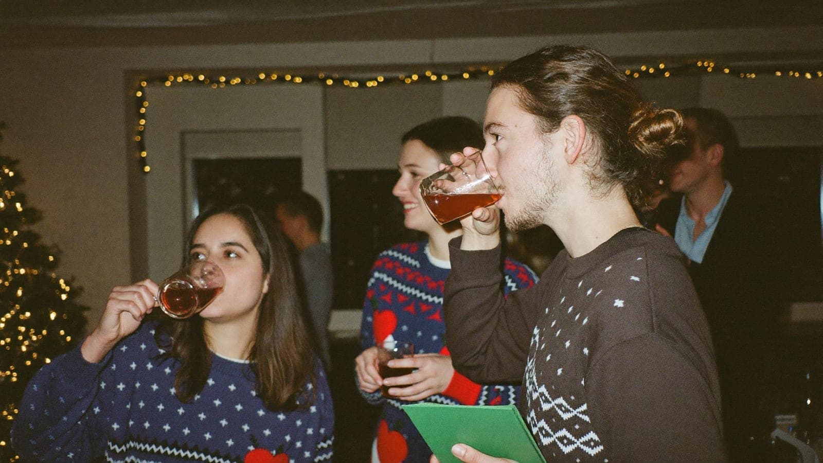 Collega's in foute kersttruien met glühwein in een versierde kantine