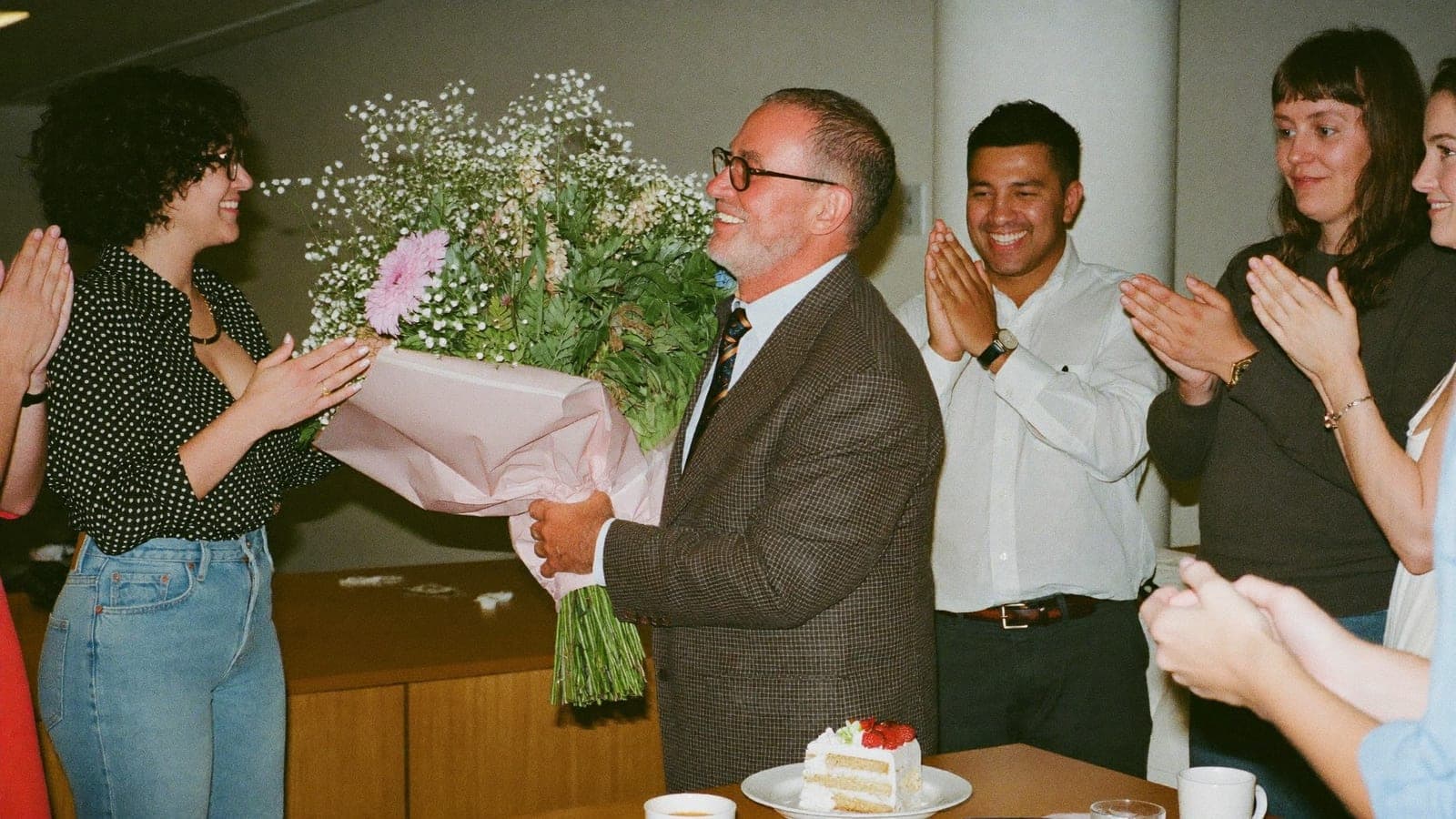 Een collega krijgt bij zijn pensioen een bos bloemen terwijl zijn collega's applaudisseren