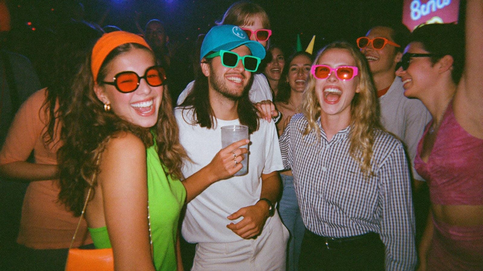 Collega's in jaren-tachtig-outfits lachen samen op de dansvloer van het personeelsfeest