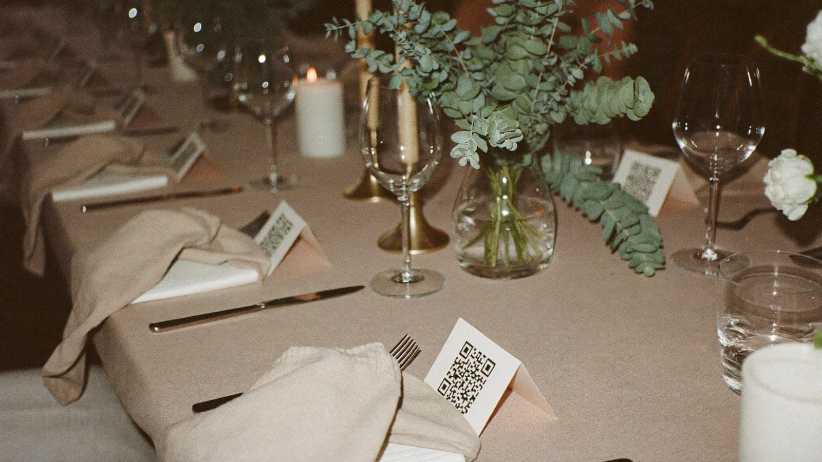 Gedekte trouwtafel met bij elk bord een kaartje met QR-code