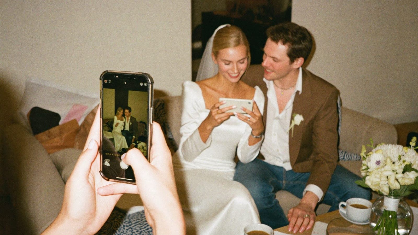 Het bruidspaar bekijkt de ochtend na de bruiloft samen foto's op een telefoon