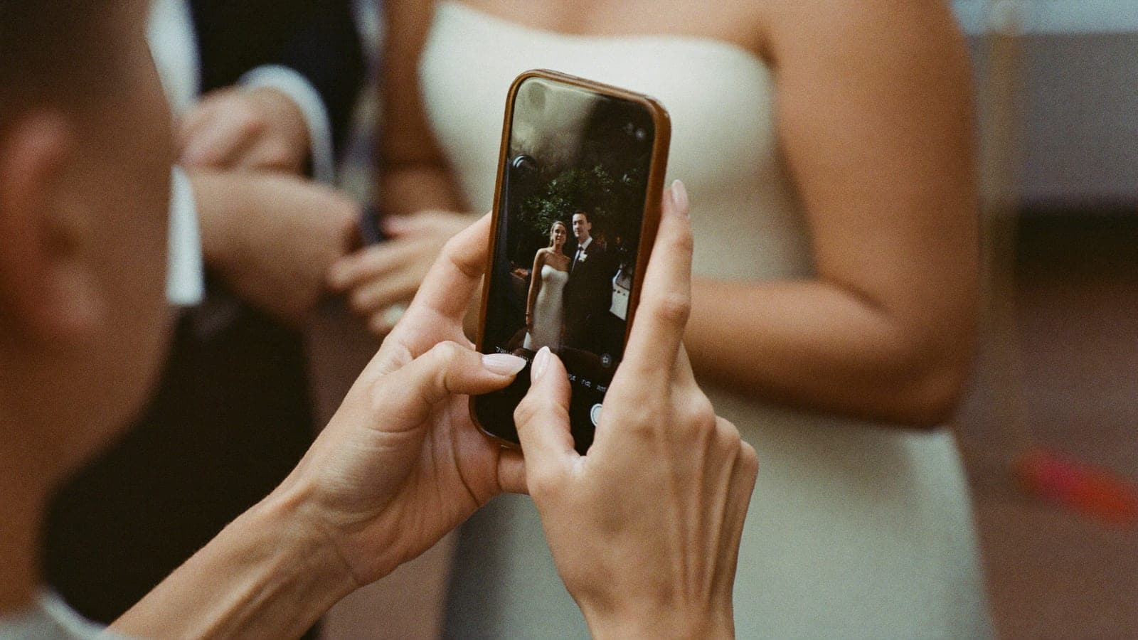Een gast bekijkt een foto van het bruidspaar op haar telefoon