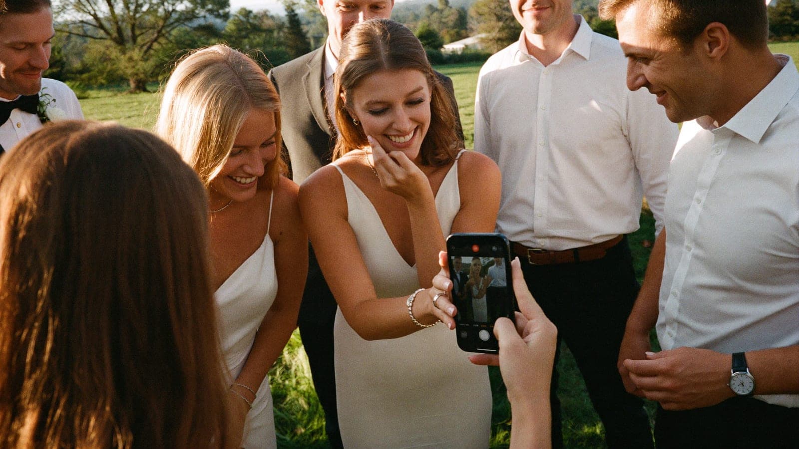 Gasten kijken lachend samen naar de foto's op één telefoon
