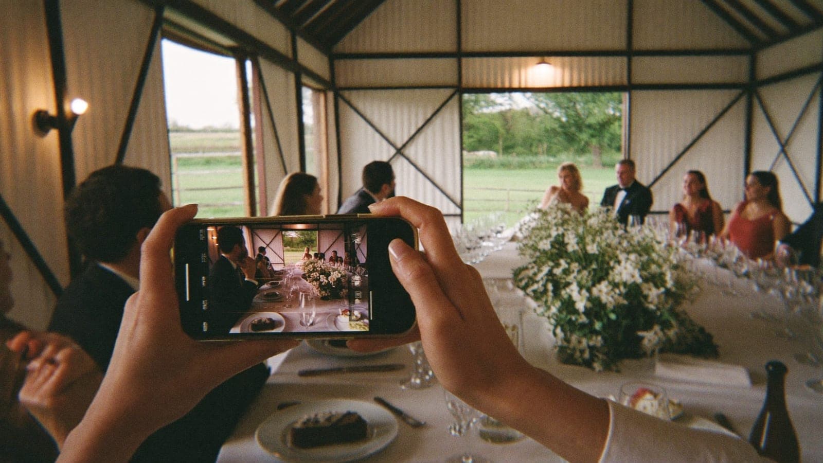 Een gast filmt met zijn telefoon de speech van de getuige tijdens het diner