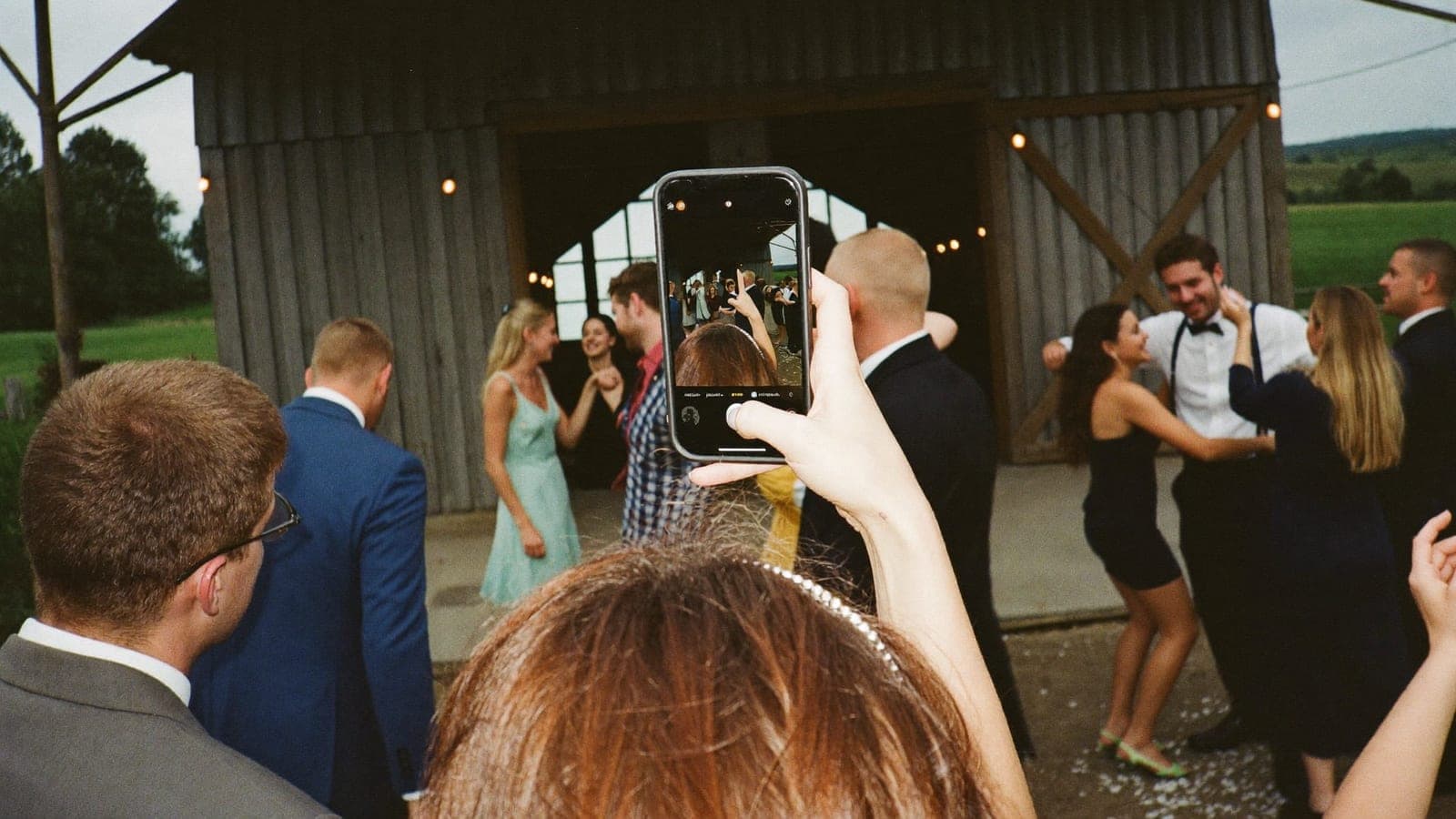Een gast maakt met de telefoon een flitsfoto van dansende vrienden op de bruiloft